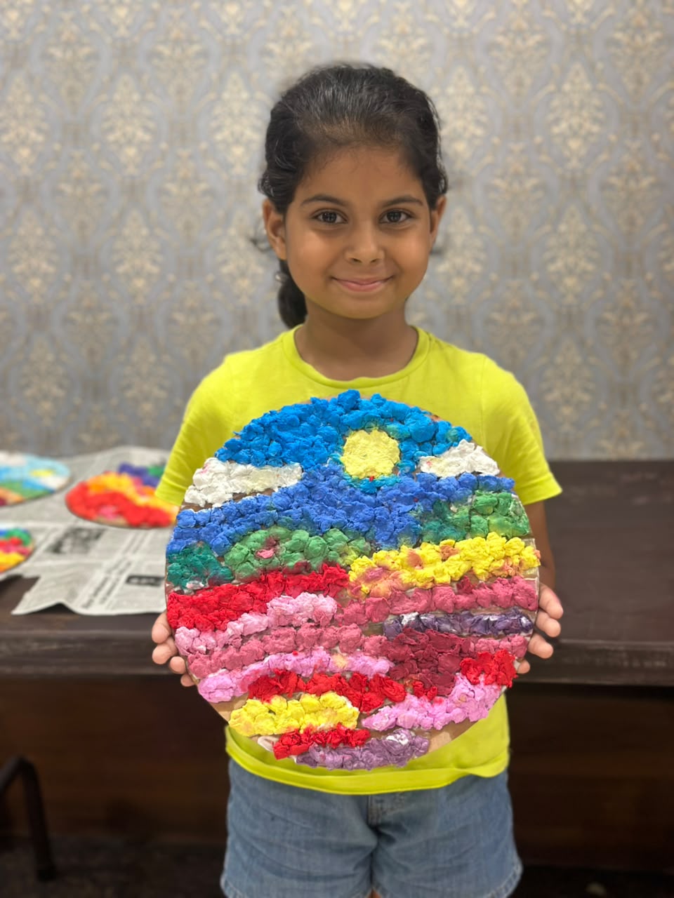 A young Skylark art student proudly holding her colourful craft work